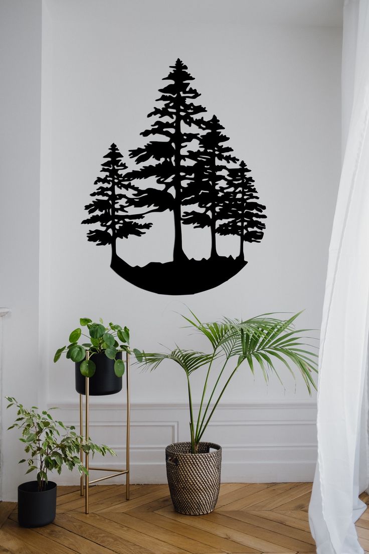 a wall decal with trees on it in a living room next to a potted plant