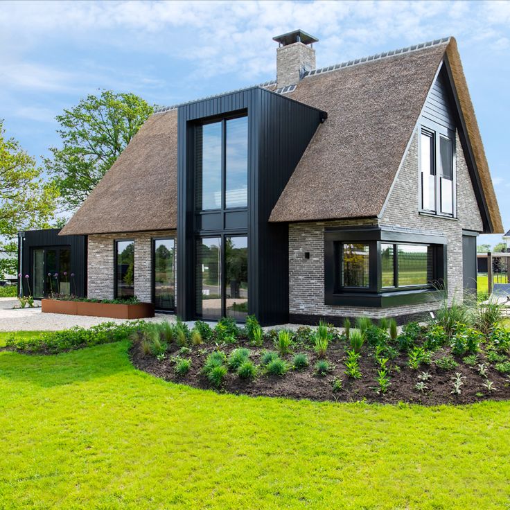 a house with a thatched roof in the middle of a grassy area next to some trees