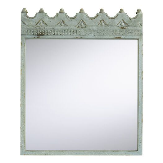 a mirror that is sitting on top of a wall with an ornate frame around it