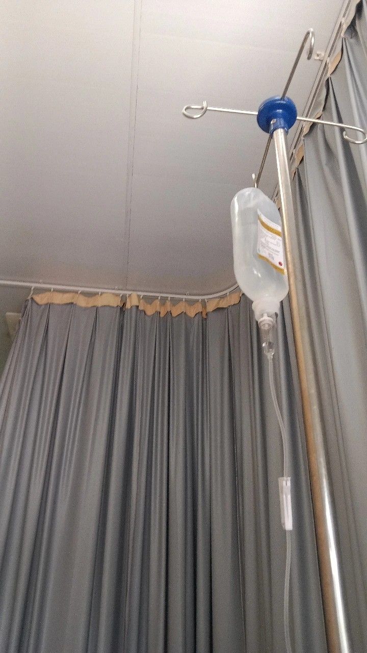 a hospital room with an iv device attached to the ceiling and drapes on the walls