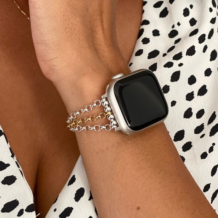 an apple watch on a woman's arm wearing a gold chain bracelet with black and white polka dots