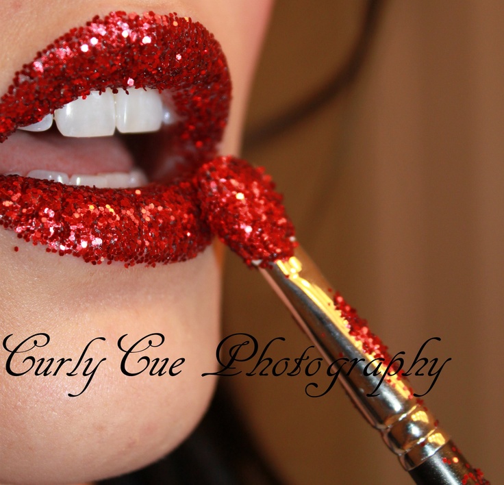 a close up of a woman's lips with red glitter on them and a brush in her mouth