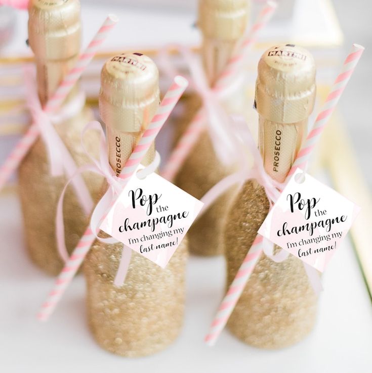 small bottles filled with sand on top of a white table covered in pink and white ribbons