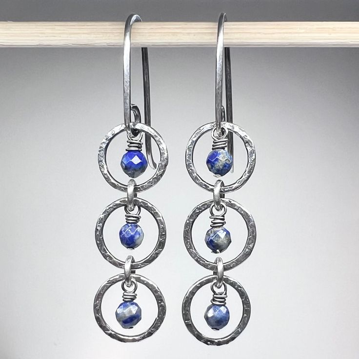 "These dangle earrings are created from genuine blue Lapis Lazuli gems and sterling silver.  The tiny natural stones are framed by a set of sterling silver circular rings.  I have created the rings by forming, soldering, and hammering them by hand.  The drops dangle from handmade sterling silver earwires.  The silver has been oxidized and polished to create an antique patina finish. Be sure to see all photos and video for size and color reference.   Lapis Lazuli: About 3.5mm Total Earring Length Handmade Sapphire Dangle Jewelry, Sapphire Hypoallergenic Drop Earrings, Hypoallergenic Sapphire Drop Earrings, Blue Sterling Silver Hoop Earrings Nickel-free, Blue Sterling Silver Hoop Earrings Nickel Free, Sapphire Sterling Silver Hoop Earrings For Gift, Sapphire Dangle Earrings In Sterling Silver, Sapphire Dangle Earrings With Natural Stones, Sapphire Sterling Silver Hoop Earrings As Gift