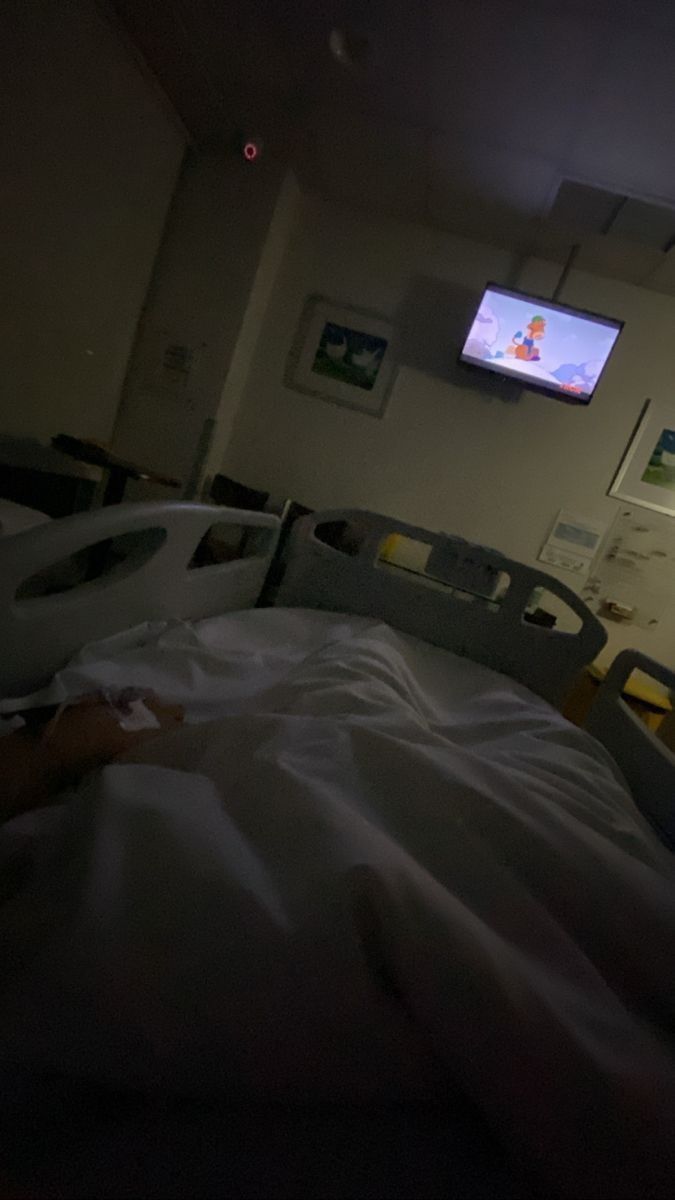 a hospital room with an unmade bed and flat screen tv on the wall above it