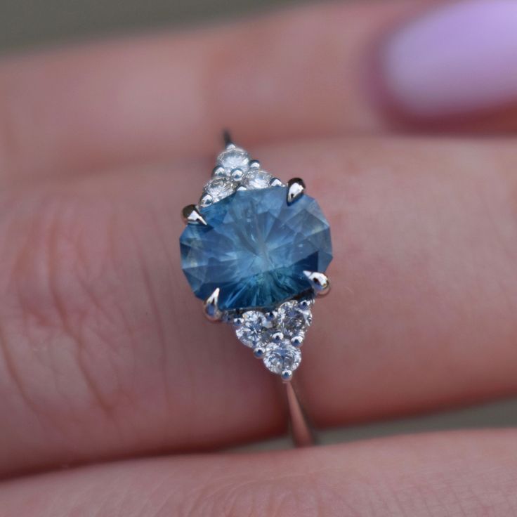 a woman's hand holding a blue and white diamond ring