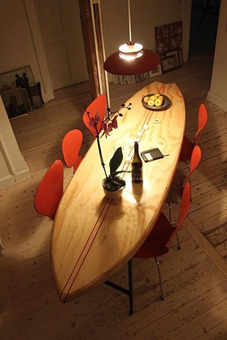 a surfboard shaped dining table with red chairs