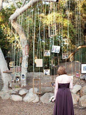 a woman standing in front of a tree with strings hanging from it's branches