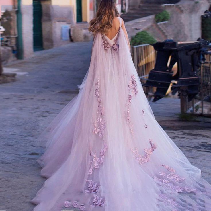 a woman in a pink wedding dress walking down the street with her back to the camera