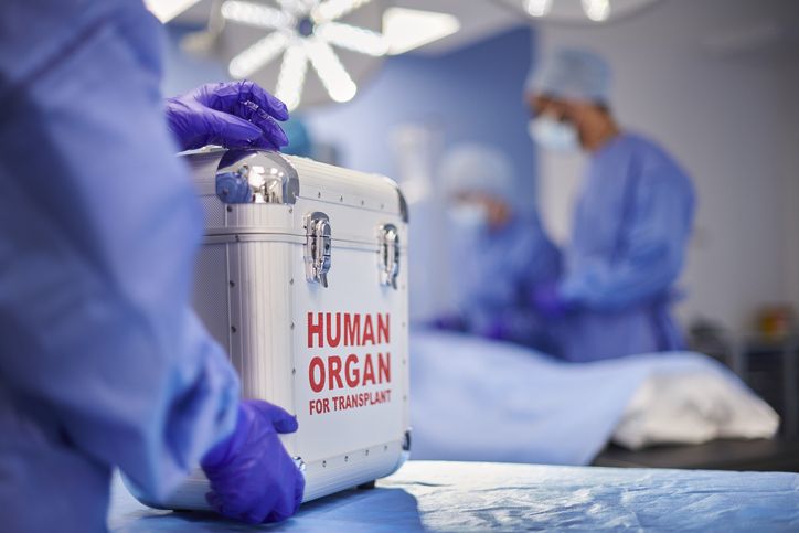 two doctors in scrubs are preparing to perform surgery on an organ box that is being held by someone else