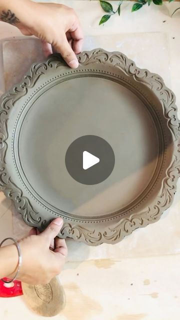 a person holding a large metal tray with an ornate design on it and the video below