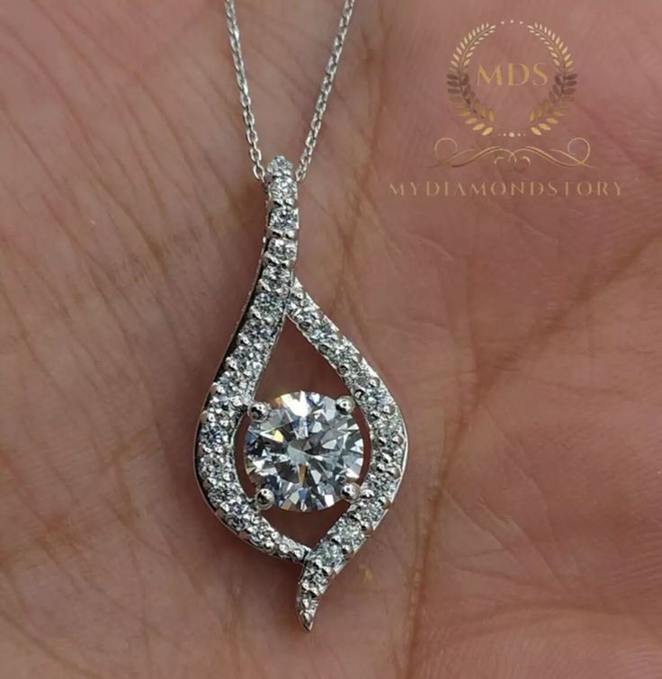 a person holding a diamond pendant in their hand