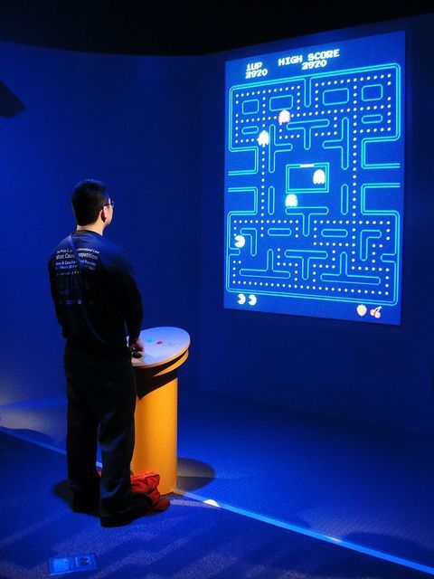 a man standing in front of a blue screen with a pacman game on it