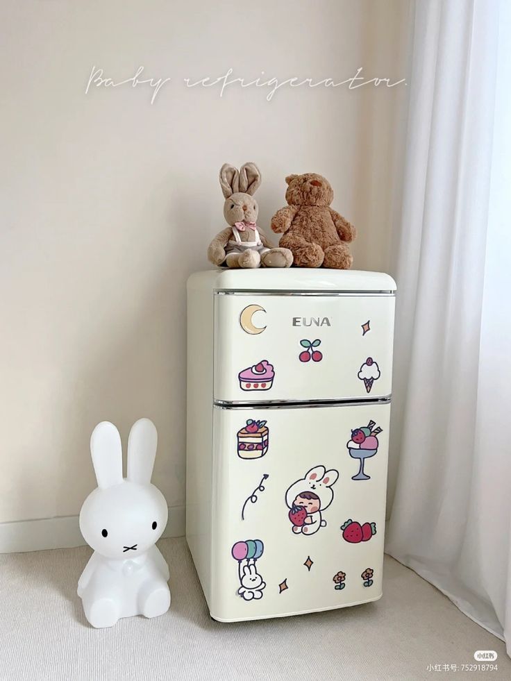 two stuffed animals are sitting on top of an old refrigerator in a room with white walls