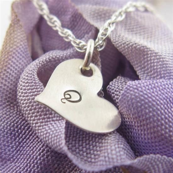 a small silver heart with the letter c on it's side hanging from a chain