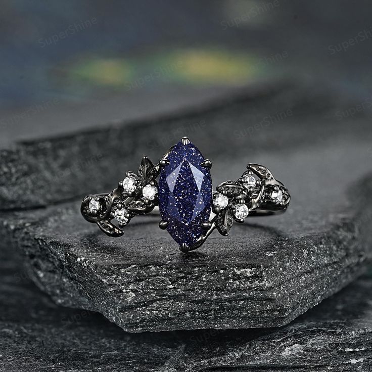 a ring with a blue stone surrounded by white diamonds on top of a black rock