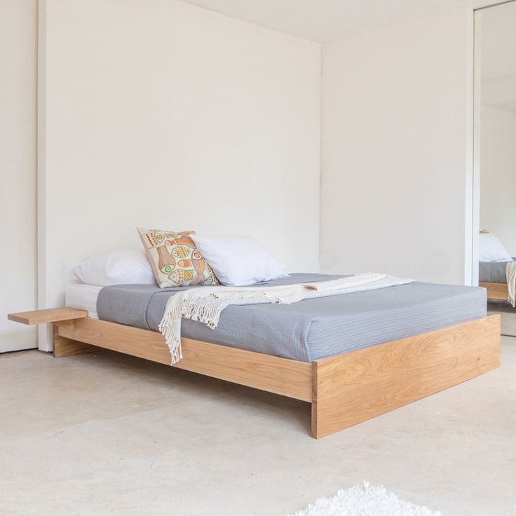 a bed sitting on top of a white floor next to a mirror