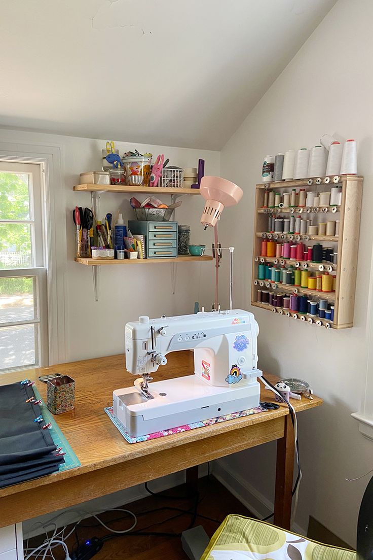 a sewing machine sitting on top of a wooden table in front of a shelf filled with craft supplies