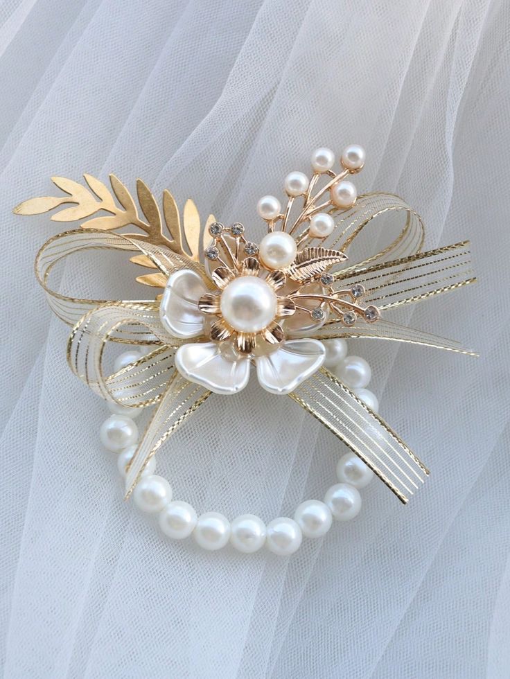 a bridal hair comb with pearls and gold leaves on white tulle fabric background