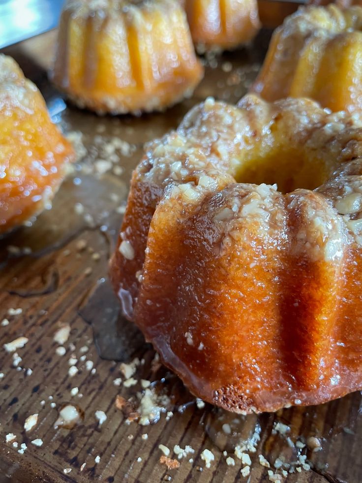 several bundt cakes on a wooden table with sugar sprinkled around them and one is cut in half