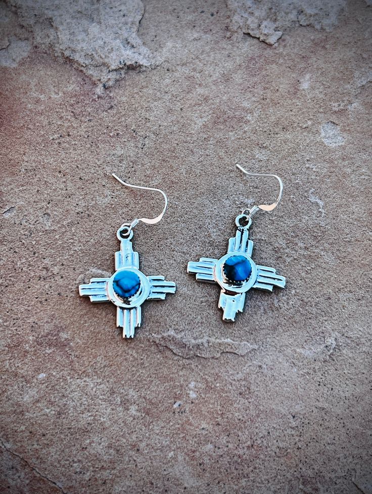 Experience the beauty of New Mexico with our Zia Symbol Turquoise Earrings. Handcrafted by Navajo artist Gregg Yazzie, these .925 sterling silver earrings feature the iconic Zia symbols and vibrant turquoise stones. Take a piece of Native American culture with you wherever you go. Southwestern Blue Drop Earrings, Southwestern Blue Earrings For Pierced Ears, Southwestern Style Blue Drop Earrings, Southwestern Style Blue Earrings For Pierced Ears, Southwestern Style Blue Pierced Earrings, Southwestern Nickel-free Jewelry As Gift, Nickel-free Southwestern Style Jewelry As Gift, Nickel Free Southwestern Jewelry For Gift, Nickel-free Southwestern Style Jewelry For Gift