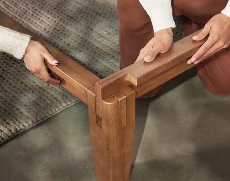 a person sitting on the ground with their hands on a wooden bench