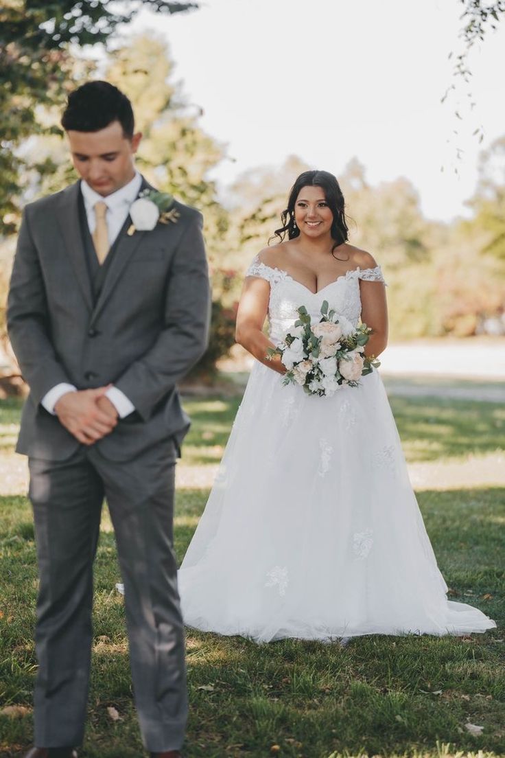 a bride and groom standing in the grass