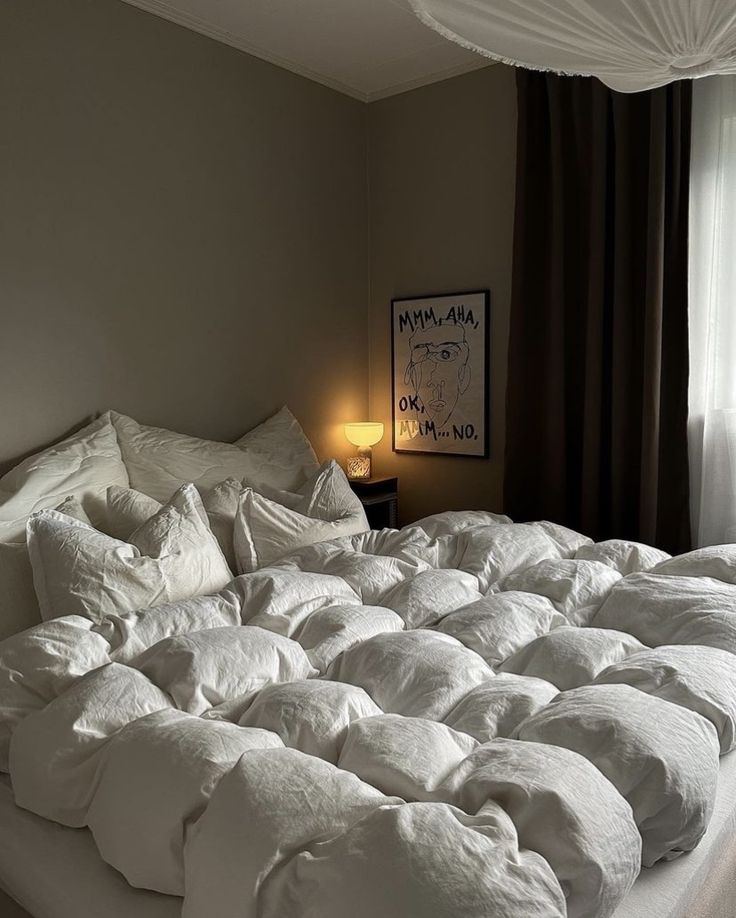 an unmade bed with white sheets and pillows in a bedroom next to a window