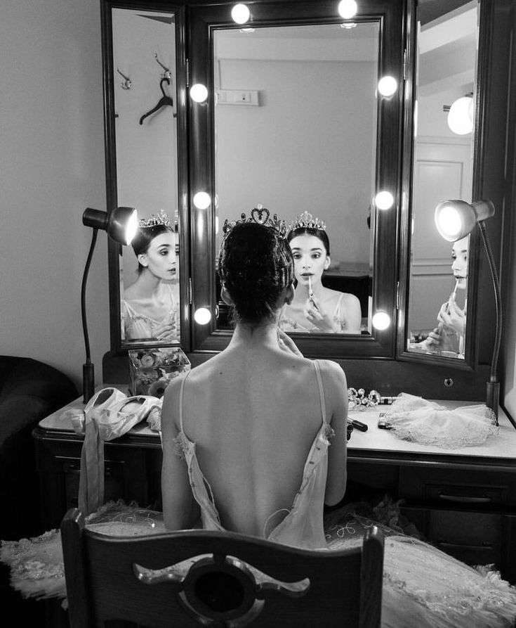 a woman sitting in front of a mirror