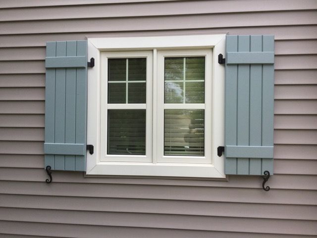 a window with blue shutters on the side of a house