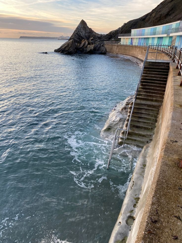 stairs leading down to the ocean with people standing on them