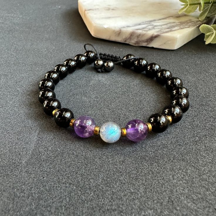 Introducing our Evil Eye Unisex Bracelet, a powerful accessory designed to provide empath protection and ward off negative energy. Handmade with a combination of Labradorite, Amethyst, and Black Tourmaline crystals, this adjustable bracelet offers a stylish and versatile design suitable for any wrist size.  * Labradorite, known for its mystical properties, enhances intuition and deflects unwanted energies. Amethyst promotes calmness and spiritual growth, while Black Tourmaline acts as a protecti Black Amethyst Crystal Bracelet In Spiritual Style, Mystical Gemstone Bracelets As Gift, Handmade Black Crystal Bracelet For Spiritual Purposes, Handmade Black Crystal Bracelet In Spiritual Style, Handmade Black Crystal Bracelet For Spiritual Healing, Handmade Black Crystal Bracelet For Spiritual Use, Black Amethyst 8mm Bead Bracelets, Black Amethyst Beaded Bracelets Spiritual, Spiritual Black Amethyst Beaded Bracelets