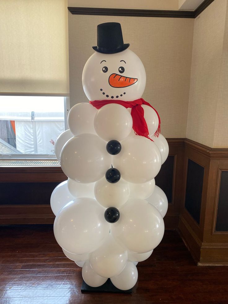 a snowman made out of balloons sitting on top of a wooden floor