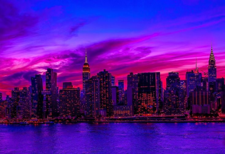 the city skyline is lit up with purple and pink colors as the sun goes down