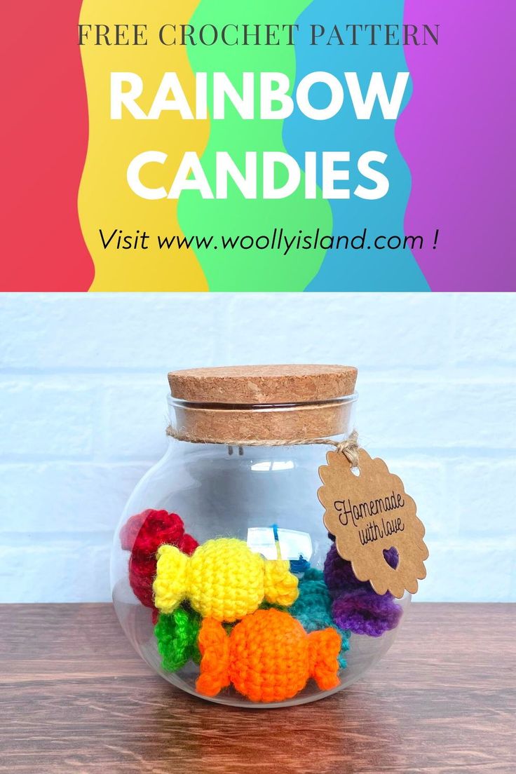 a glass jar filled with crochet rainbow candies on top of a wooden table