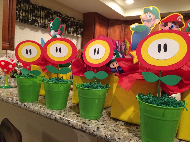 mario birthday party decorations on a kitchen counter with potted plants and paper cutouts