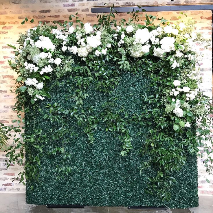 an artificial green wall with white flowers and greenery