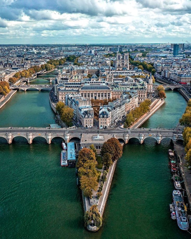 an aerial view of the city of paris, with bridges and boats in the water