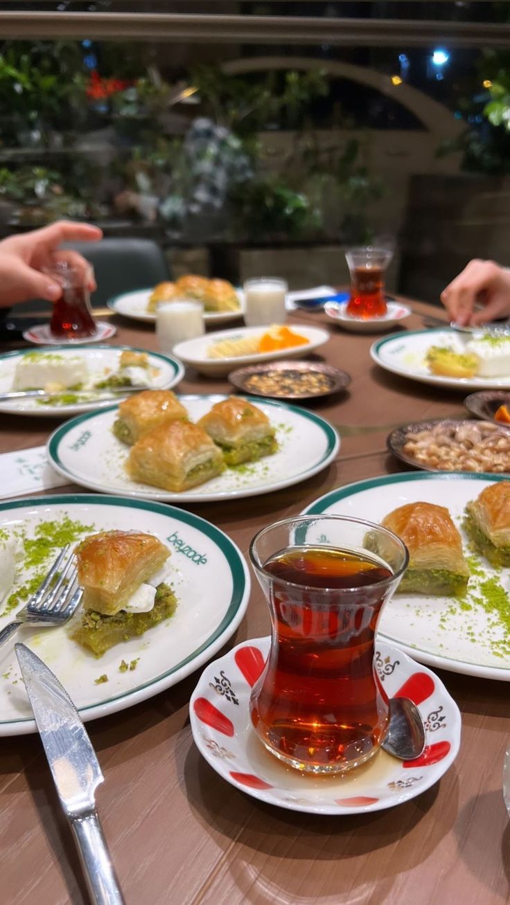 people sitting at a table with plates of food and cups of tea in front of them