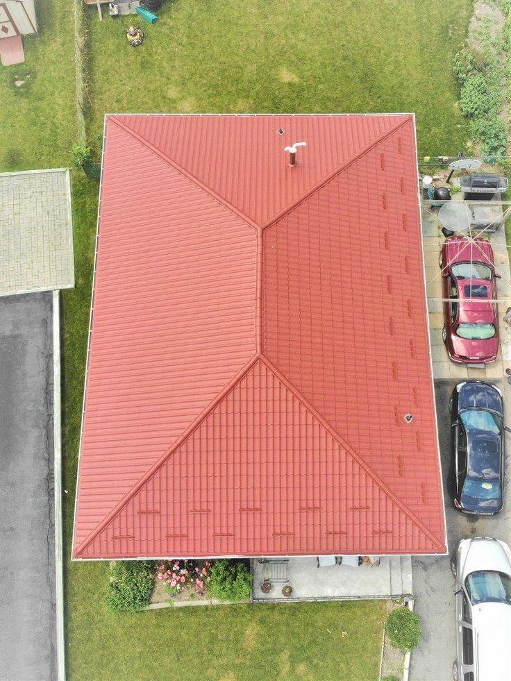 an overhead view of a red roof with cars parked in the parking lot behind it