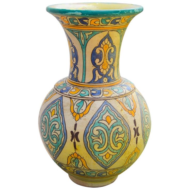 an ornate vase with blue, yellow and green designs on it's sides against a white background