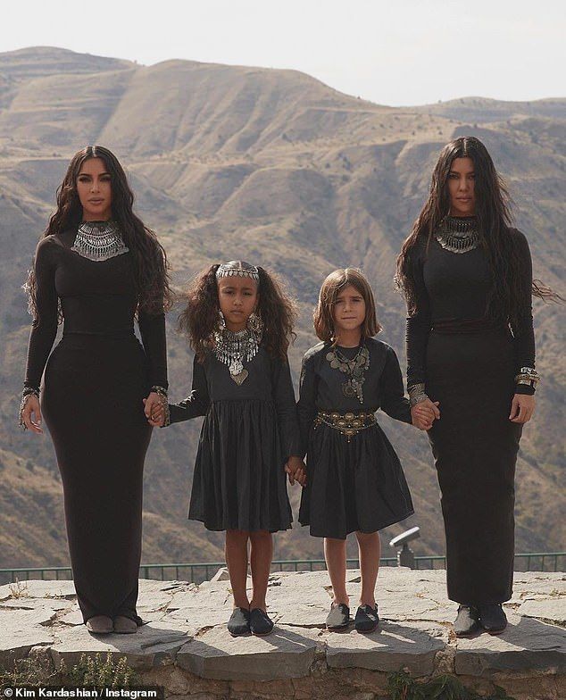 three women and two children standing on top of a hill with mountains in the background