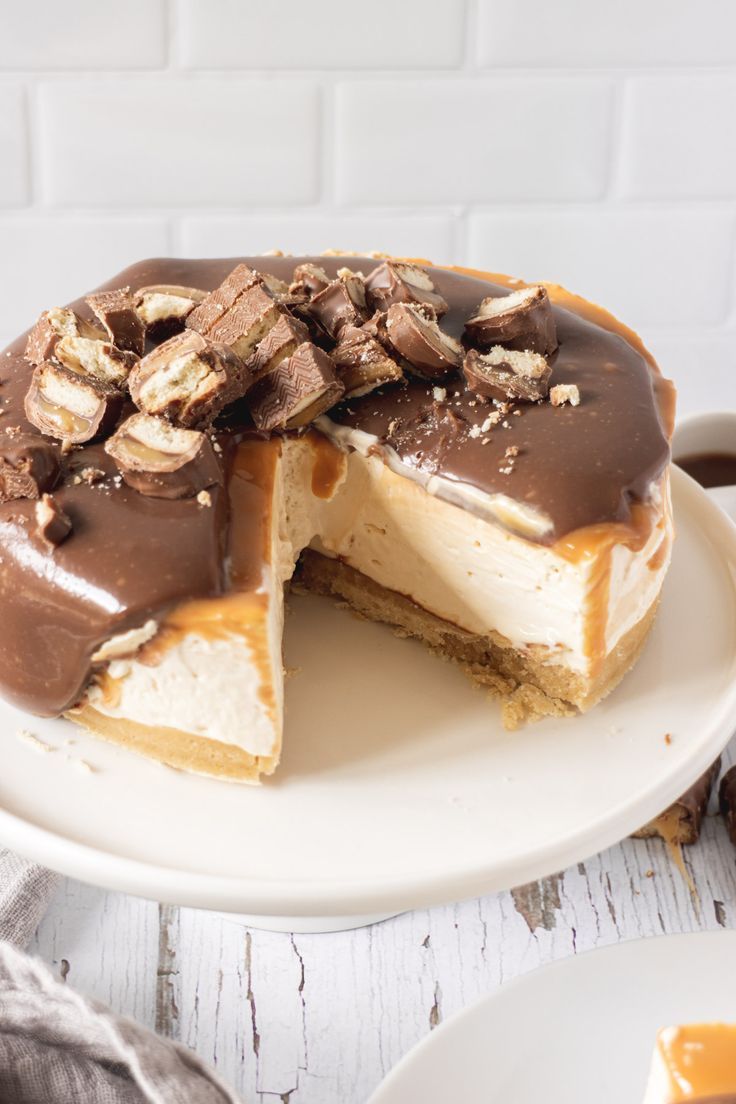 a chocolate and peanut butter cheesecake on a white plate with one slice cut out