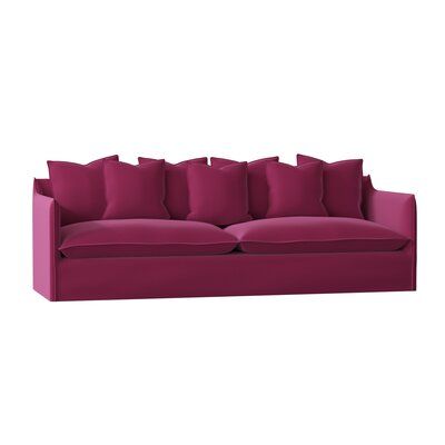 a pink couch with many pillows on it's back and side ends, facing the camera