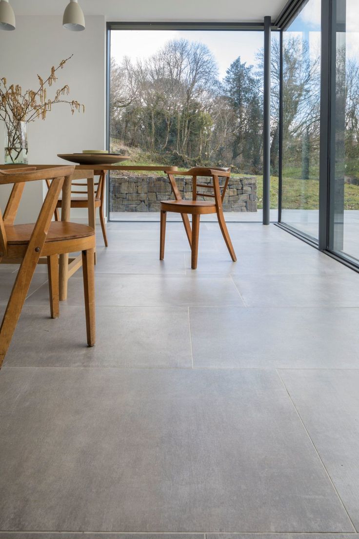 a dining room with wooden chairs and table in front of large glass doors that look out onto the outdoors