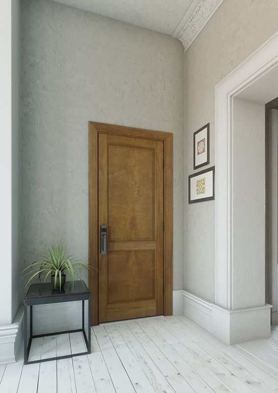 an empty room with a wooden door and small plant on the floor next to it