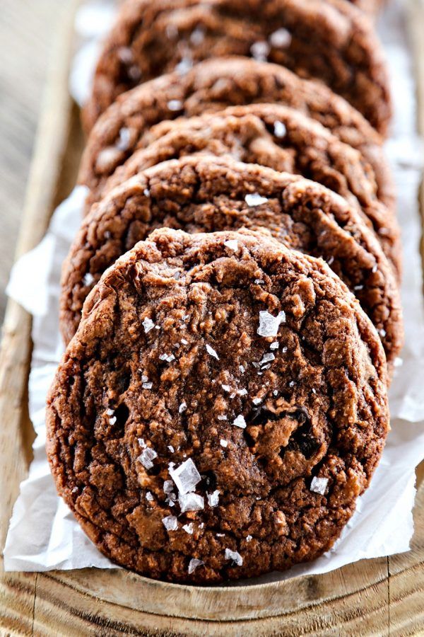 chocolate cookies with sea salt on top are lined up in a wooden tray, ready to be eaten