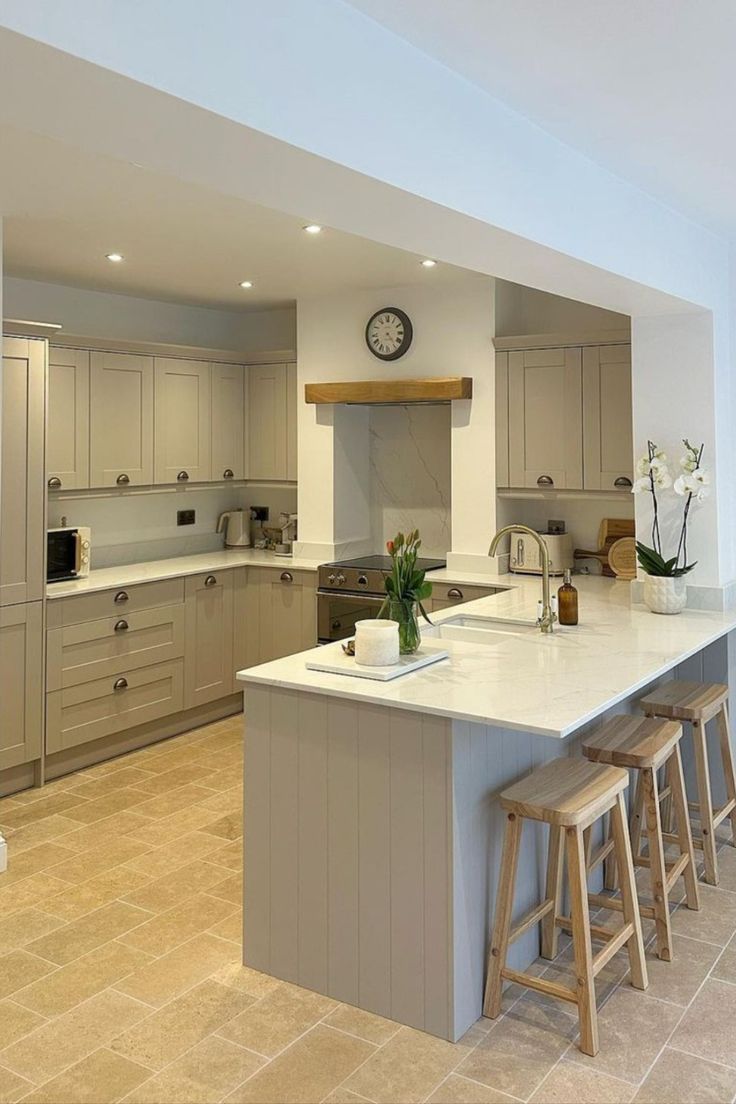 a large kitchen with an island in the middle and three stools at the end