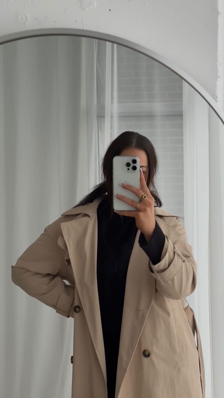 a woman taking a selfie in front of a mirror with her cell phone up to her ear