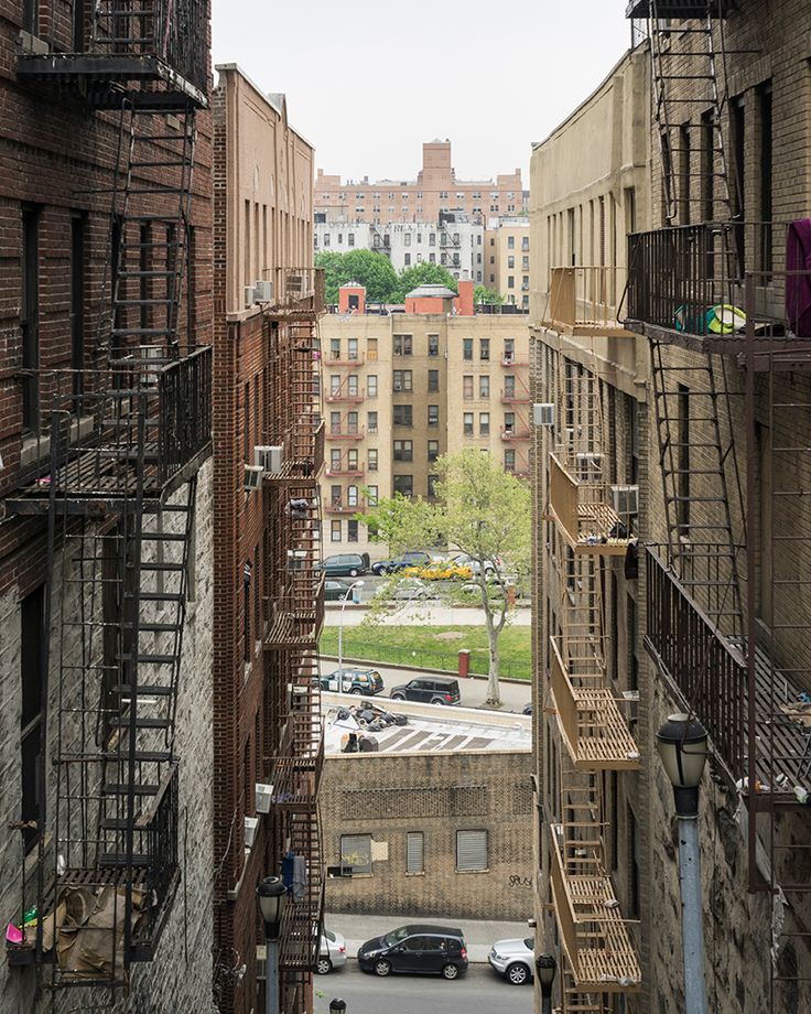 an alley way with fire escapes and cars parked on the side